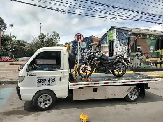Grúa llevando una moto por un barrio de Bogotá