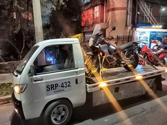 Grúa con moto adventure de noche, con las luces encendidas